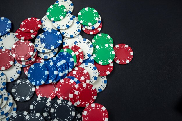 Classic colored round poker chips scattered on a black table