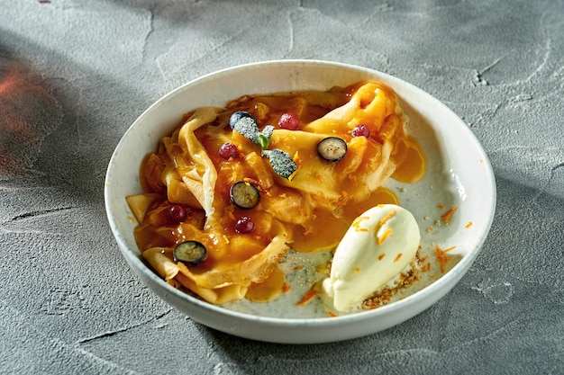 Classic crepe suzette with orange jam ice cream and berries in a plate A delicious dessert