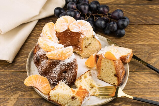 Classic English Christmas cake with tangerines on a ceramic plate. side view. wooden background.