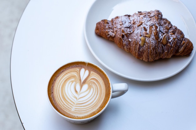 Classic French almond croissant and coffee white cup with cappuccino