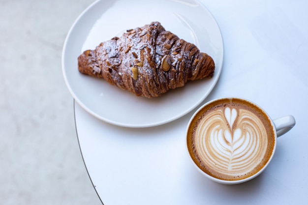 Classic French almond croissant and coffee white cup with cappuccino