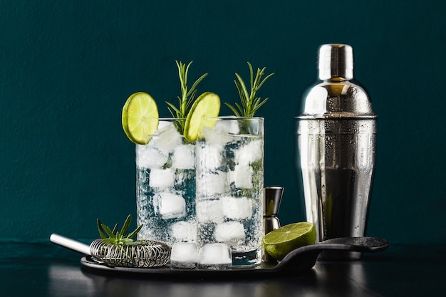 Classic gin and tonic cocktail with rosemary sprigs in tall glasses on a table with bar accessories