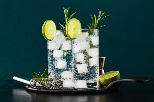 Classic gin and tonic cocktail with rosemary sprigs in tall glasses on a table with bar accessories