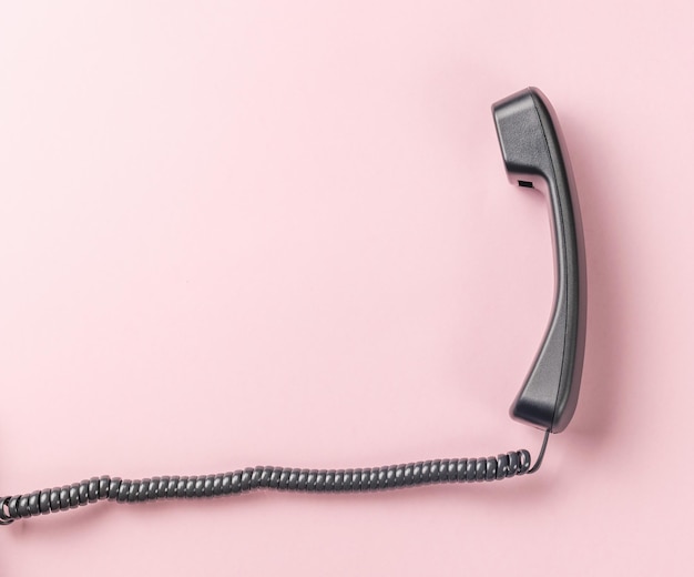 Classic handset with a wire on a pink background