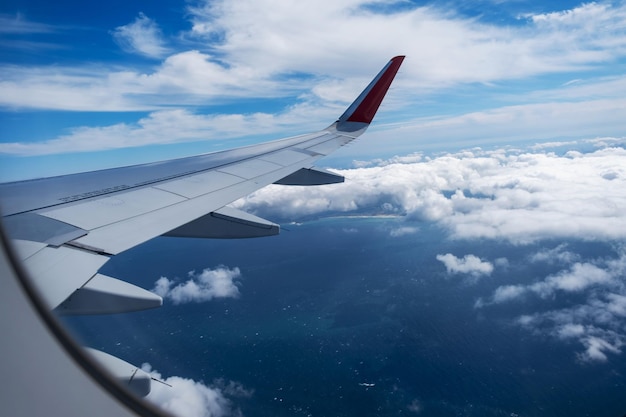 Classic image through aircraft window onto wing flight view over sea in cloudy weather