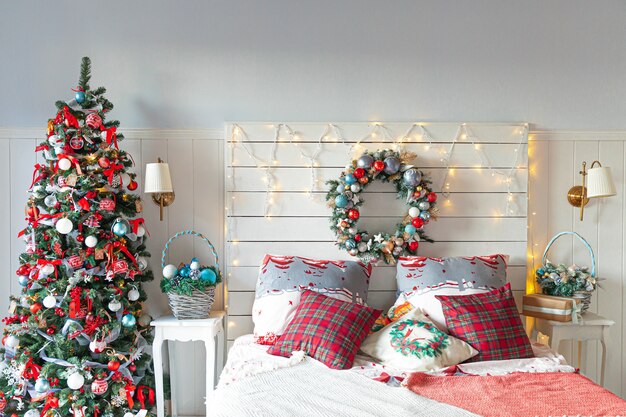 Classic interior room with Christmas tree and traditional white red decorations. Modern clean white classical style interior design apartment bedroom. Christmas eve at home. Minimalist home design.