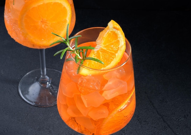 Classic italian aperitif aperol spritz cocktail in two glass with ice orange on black background close up