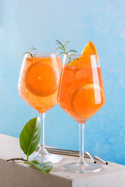 Classic italian aperitif aperol spritz cocktail in two glass with ice orange on blue background on