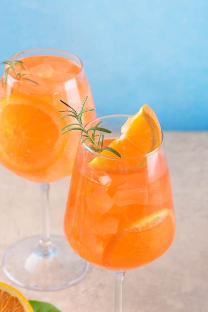 Classic italian aperitif aperol spritz cocktail in two glass with ice orange on blue background on