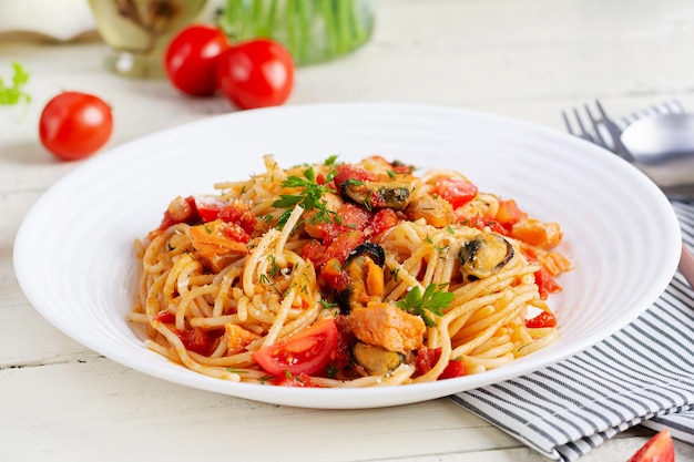 Classic italian pasta spaghetti marinara with mussels and salmon on white table Spaghetti pasta with sauce marinara