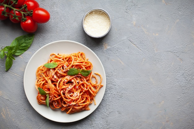 Classic italian pasta with tomato sauce, cheese parmesan and basil on white plate