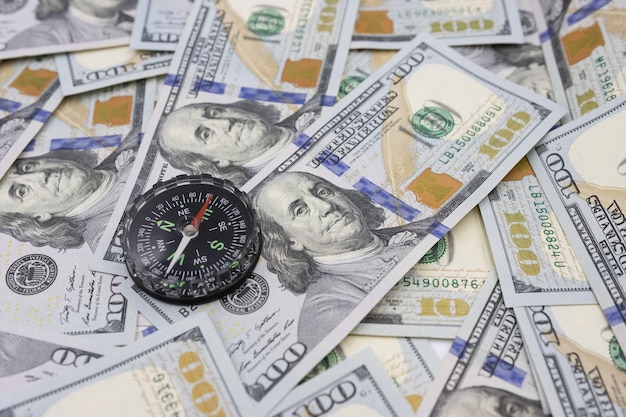 Classic navigational compass on the background of one hundred dollar bills