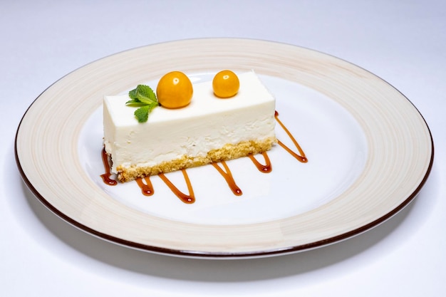 Classic new york cheesecake with physalis and syrup on a white plate and background delicious