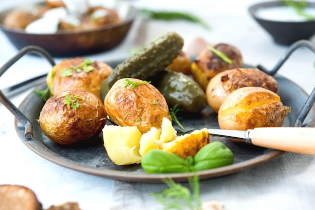 Classic Russian dish baked potatoes with sour cream and herbs and pickles. Horizontal photo.