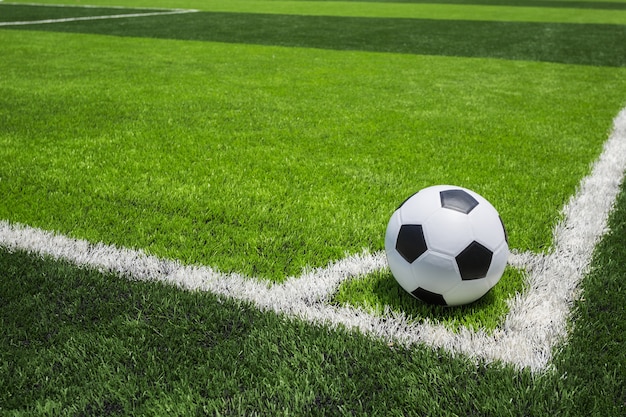 Classic soccer ball on artificial bright and dark green grass