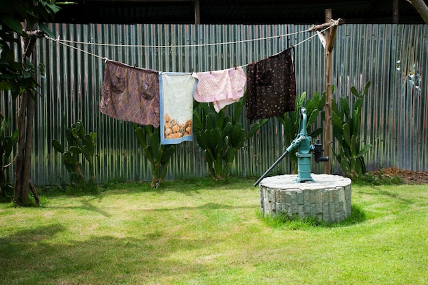 Classic vintage retro antique manual pump water ground of artesian water well and drying clothes for thai people use at outdoor garden park at rural countryside in Nonthaburi Thailand