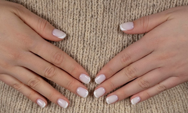 Classic white manicure on natural wool background