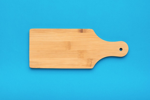 Classic wooden cutting board on a light blue background Flat lay