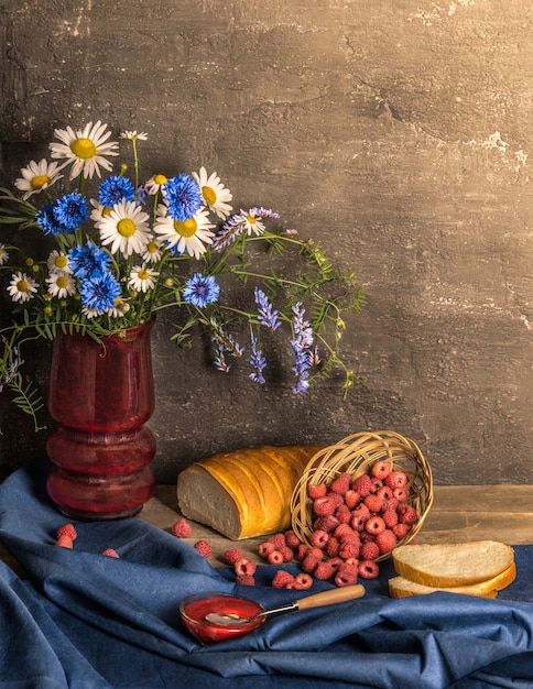 Classical still life with summer harvest raspberry, bread and flowers