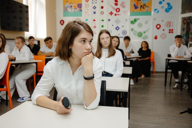 A classroom with a girl sitting at a desk and a wall with a sign that says'school of education '