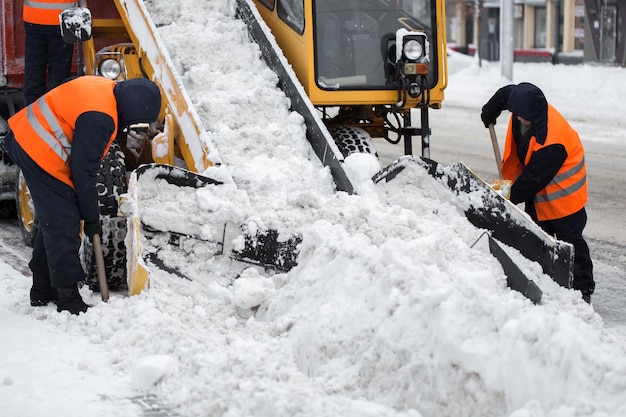 Claw loader vehicle removes snow from the road. Employees of municipal services helps shovel snow