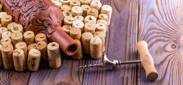 Clay bottle metal corkscrew and cork on a wooden table