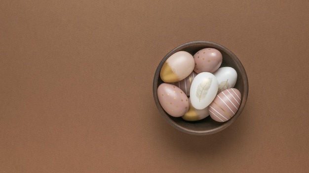 Clay bowl with Easter eggs on a brown background Flat lay