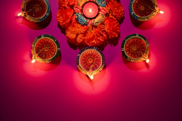 Clay Diya lamps lit  during Dipavali celebrate on pink background