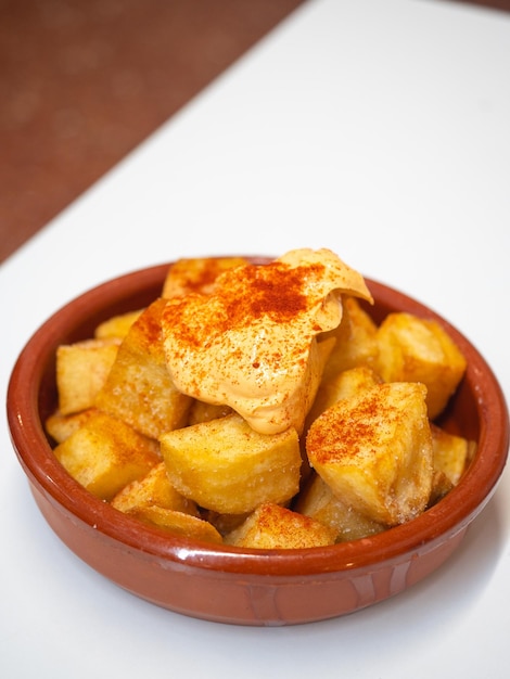 Clay pot with patatas bravas a traditional Spanish tapa Fried potatoes with spicy sauce