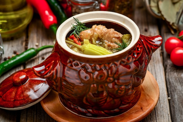 Clay pots with baked potatoes and chicken meat with pumpkin and choped greens on a wooden plank