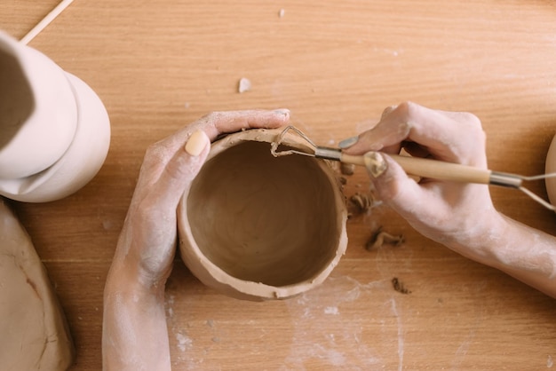 Clay potter's hands carve a pattern on the bowl View from above Ceramics and clay for creativity in the workshop