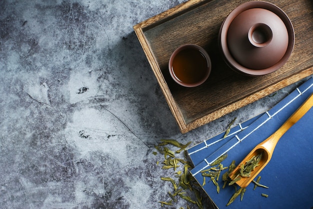 Clay tea set and tea book on dark cement background