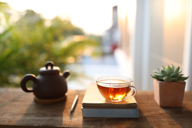 clay teapot and cup with succulent plant and books on old wooden table