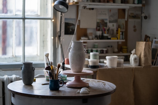 Clay vase stands on wooden rack drying up on table and prepared for sketch for exhibition in museum