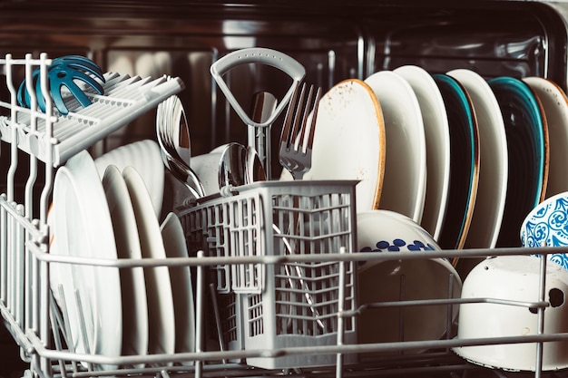 Clean dishes in an open dishwasher in a home kitchen closeup