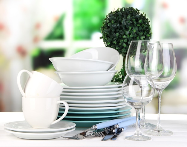 Clean dishes on table on window background