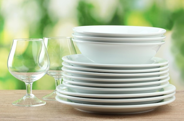 Clean dishes on wooden table on green background