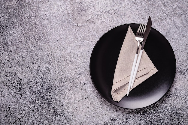 Clean empty black plate with cutlery