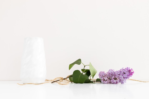 Clean notepad with spring lilac flowers on white wooden background