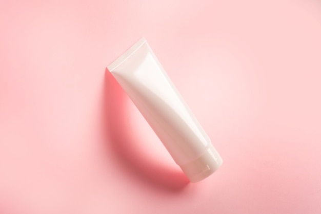 Clean plastic tube with body cream on pink background