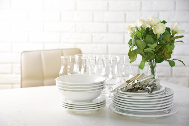 Clean plates glasses and cutlery on white table