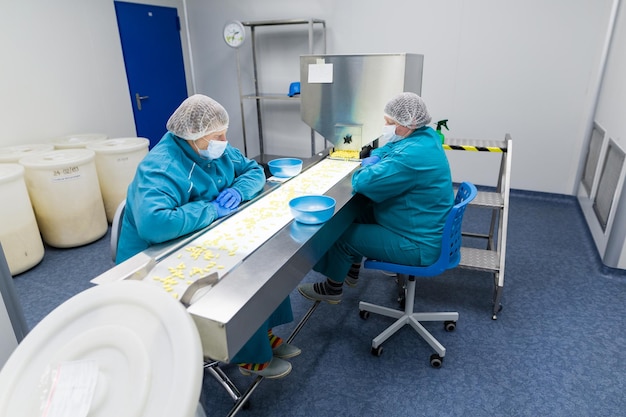 Clean room two women work on line with pills