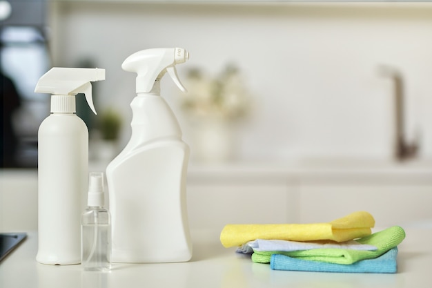 Clean up close up shot of detergent bottles and stack of rugs on kitchen surface