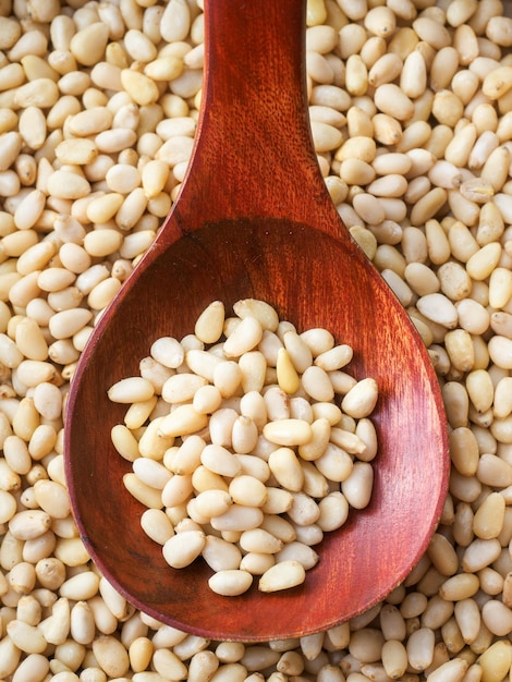 Cleaned pine nuts Pine nut kernels lie in wooden spoon Top view of nuts closeup Advertising photography for marketplaces or online stores