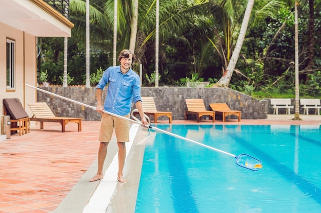 Cleaner of the swimming pool  man in a blue shirt with cleaning equipment for swimming pools sunny