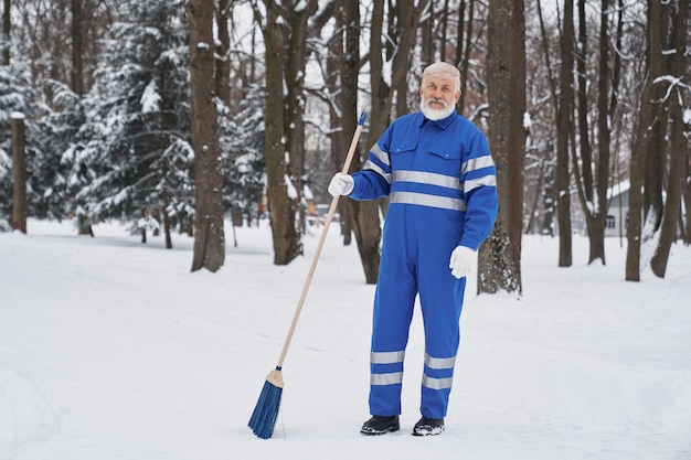 Cleaner in work overalls with broom.