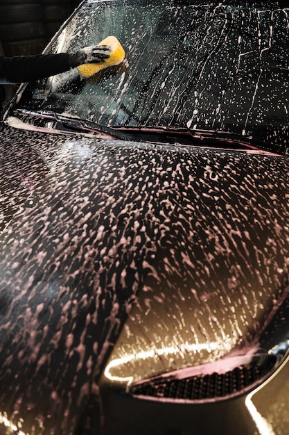 Photo cleaning the car windscreen using a sponge ensuring a thorough removal of dirt and grime for optimal visibility