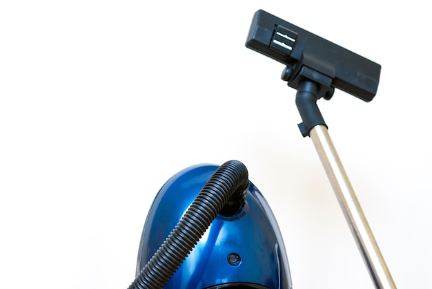 Cleaning concept blue vacuum cleaner on white studio wall close up