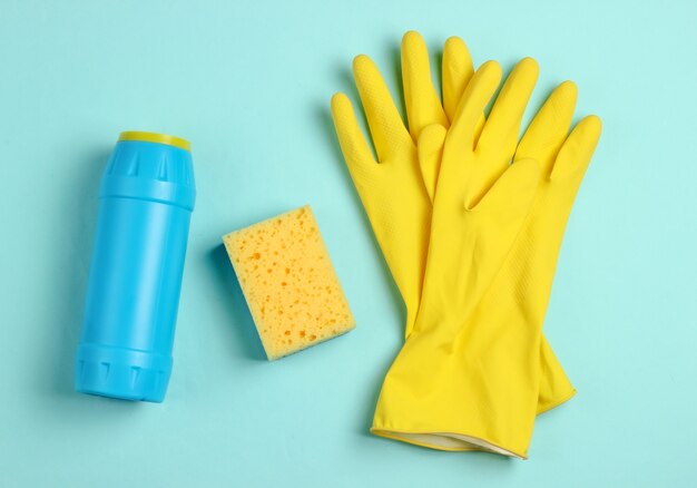 Cleaning concept. Detergent bottles, sponges, gloves on blue background