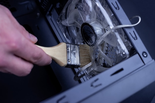 Cleaning dirty desktop computer processor fan from dust by special brush close up